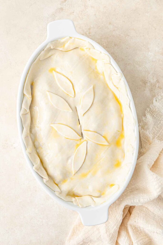 The pastry covering the pie in a pie dish, ready for the oven.