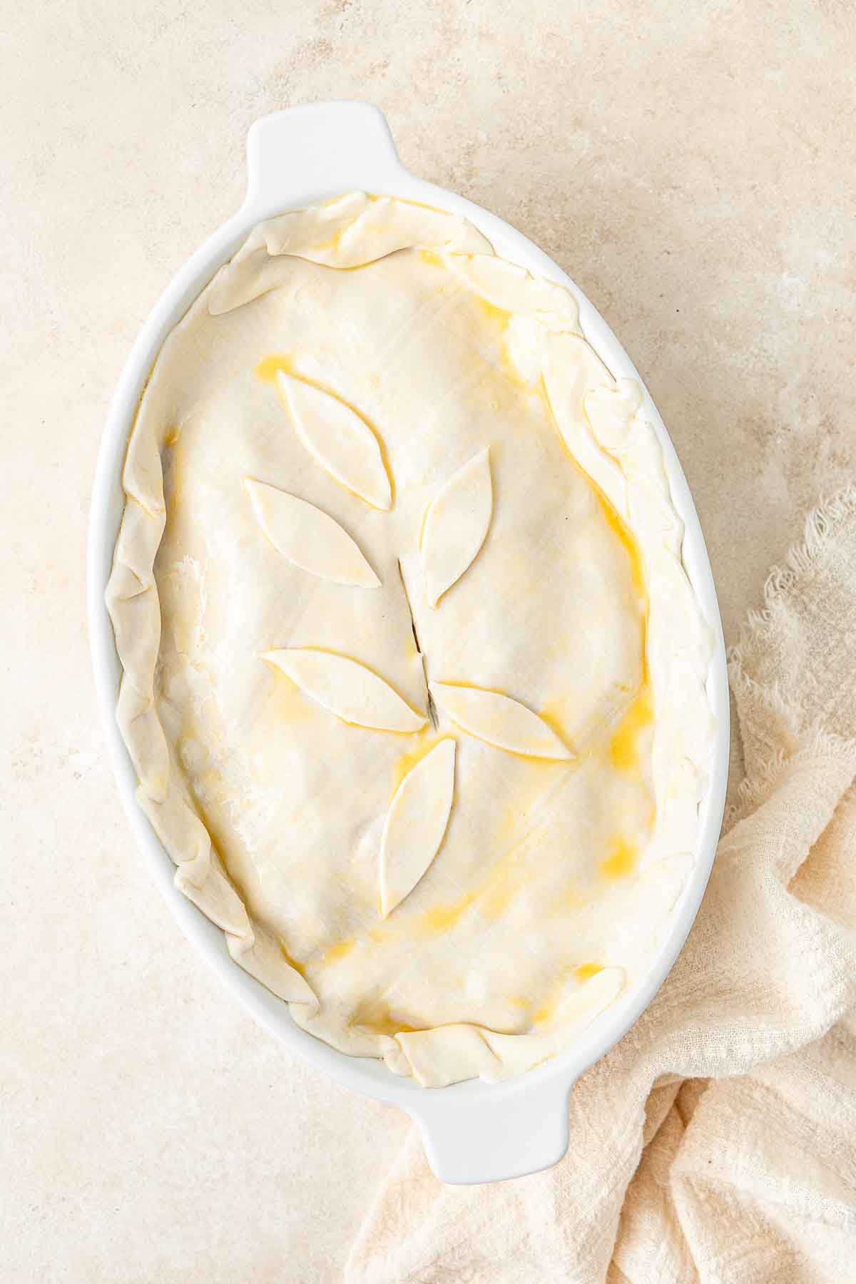 The pastry covering the pie in a pie dish, ready for the oven.