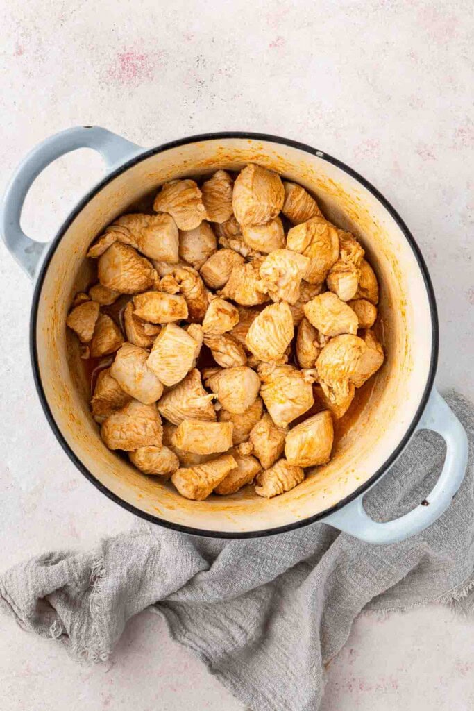 Cooking the chicken pieces in a Dutch oven.