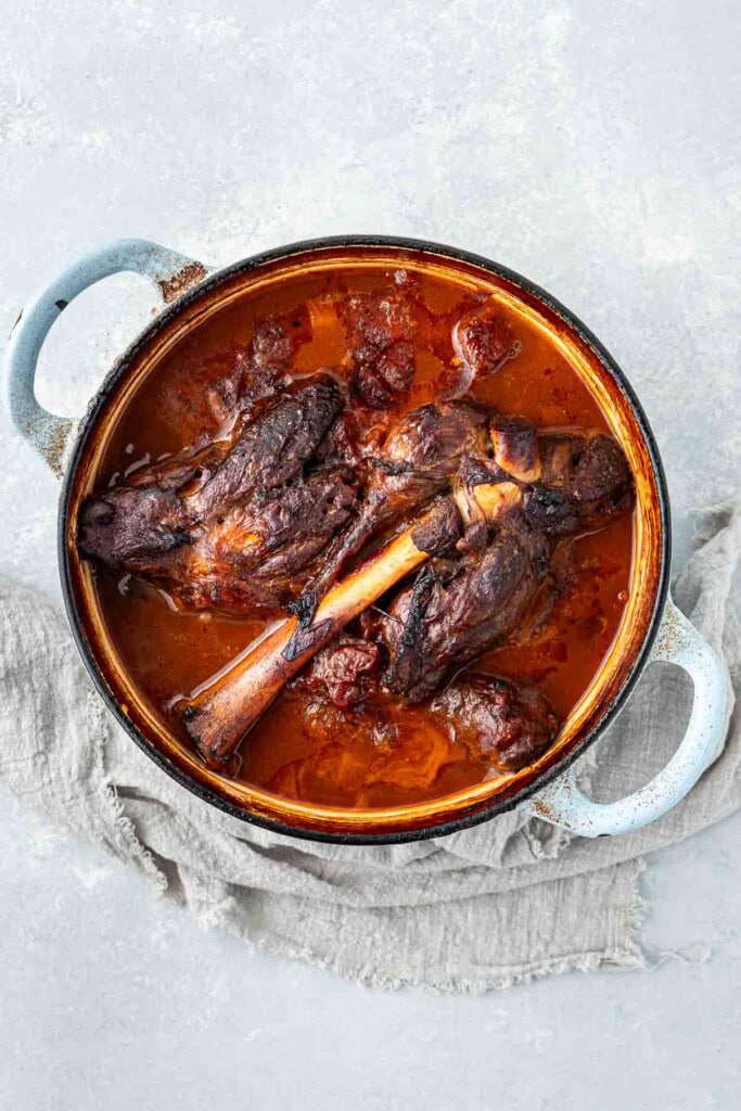 Braised lamb shanks in a large cast iron pot.