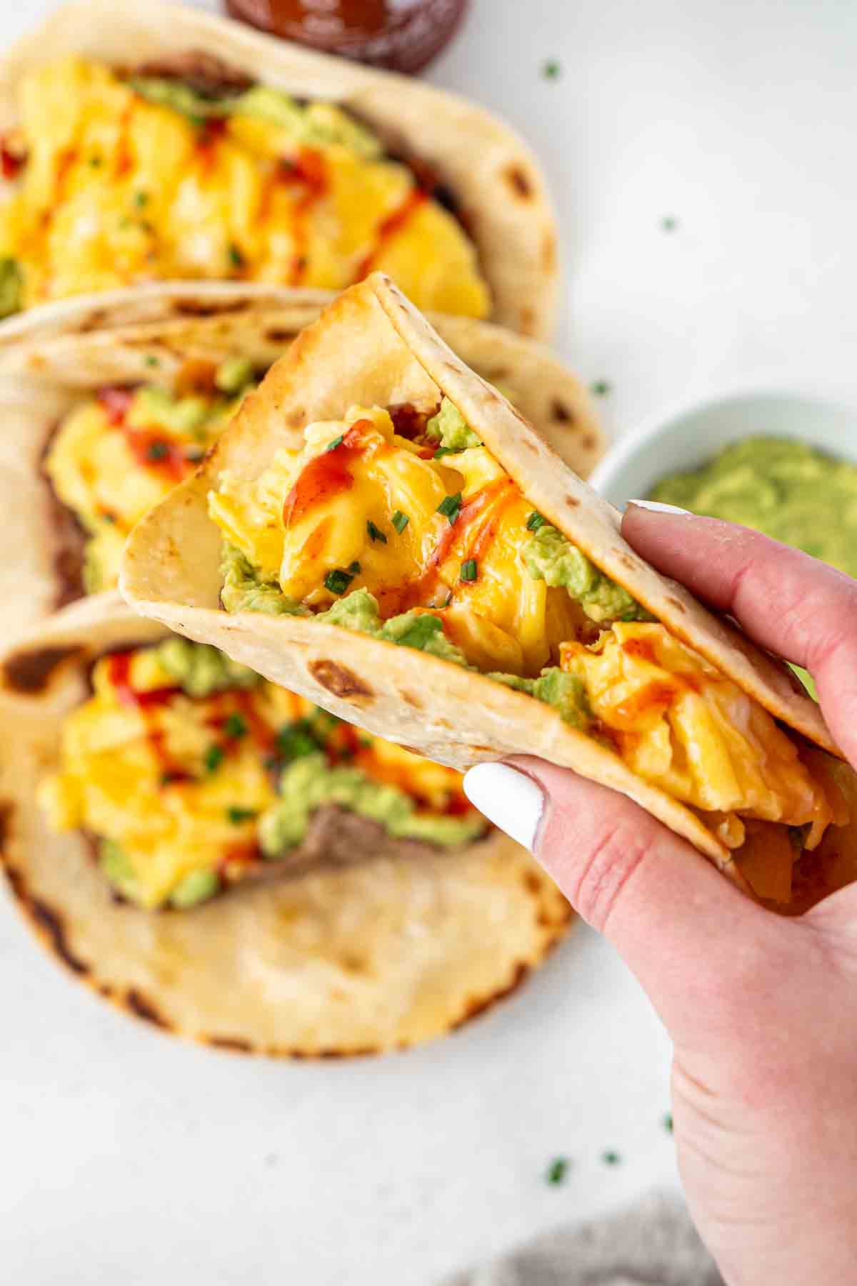 Close up of a hand picking up a breakfast taco.