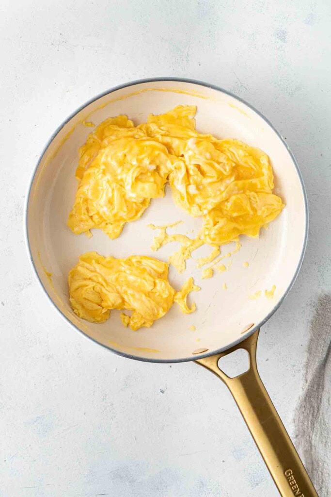 Soft scrambled eggs in a frying pan.