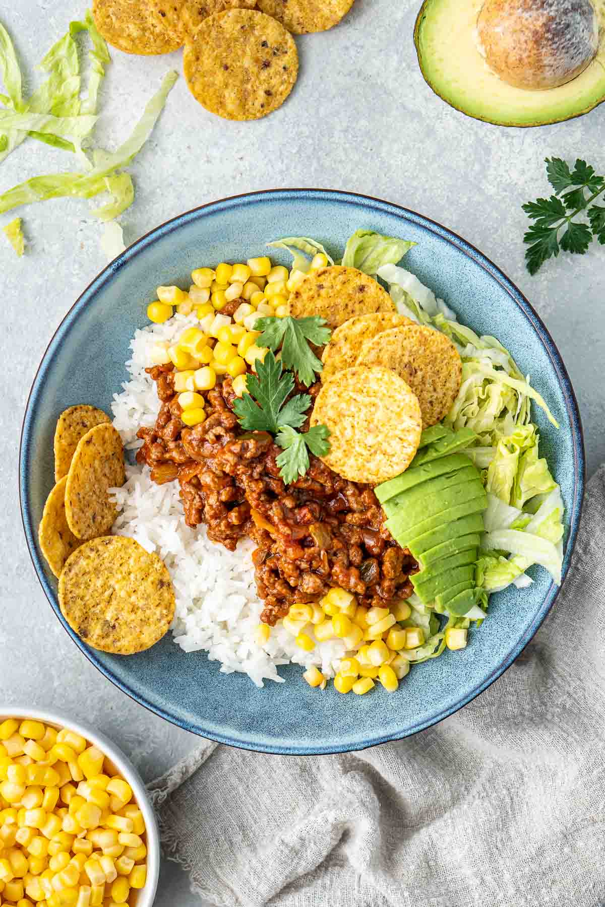 Beef taco bowls in a bowl with avocado and corn chips.