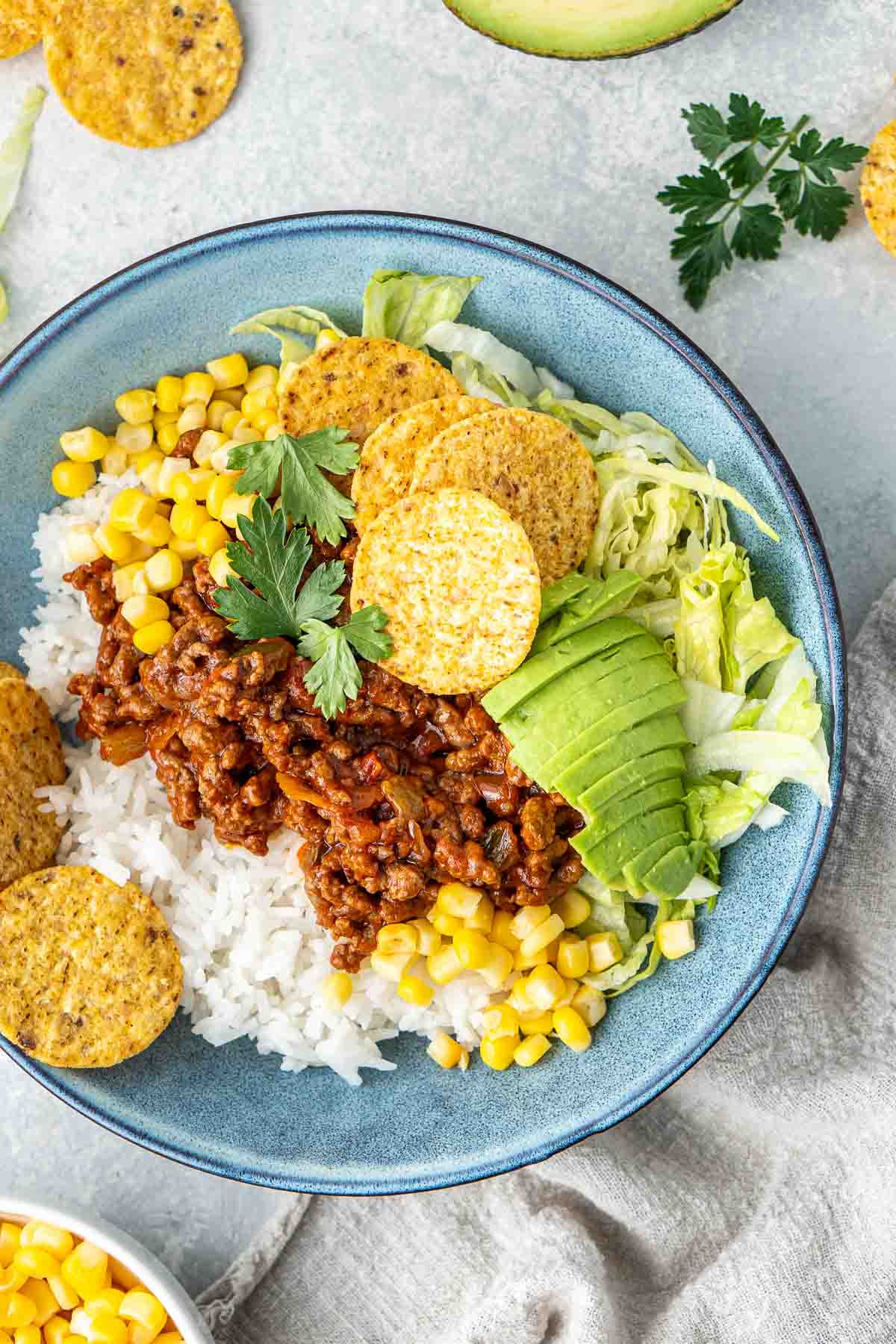 Beef taco bowls in a bowl with avocado and corn chips.