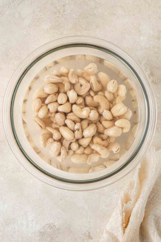 Cashews soaking in a bowl of boiling water.