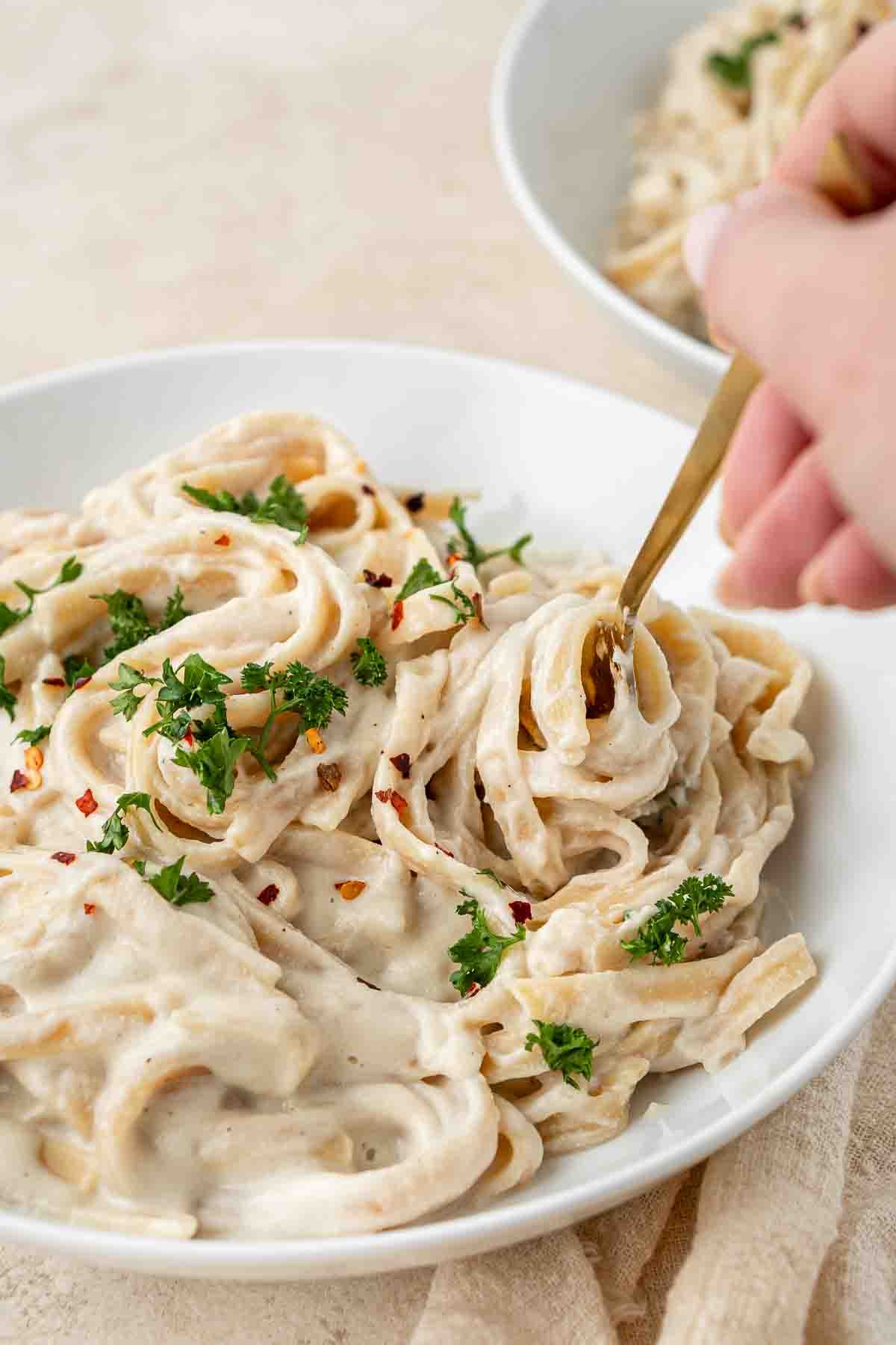 For taking a bite of vegan cauliflower alfredo from a white bowl.