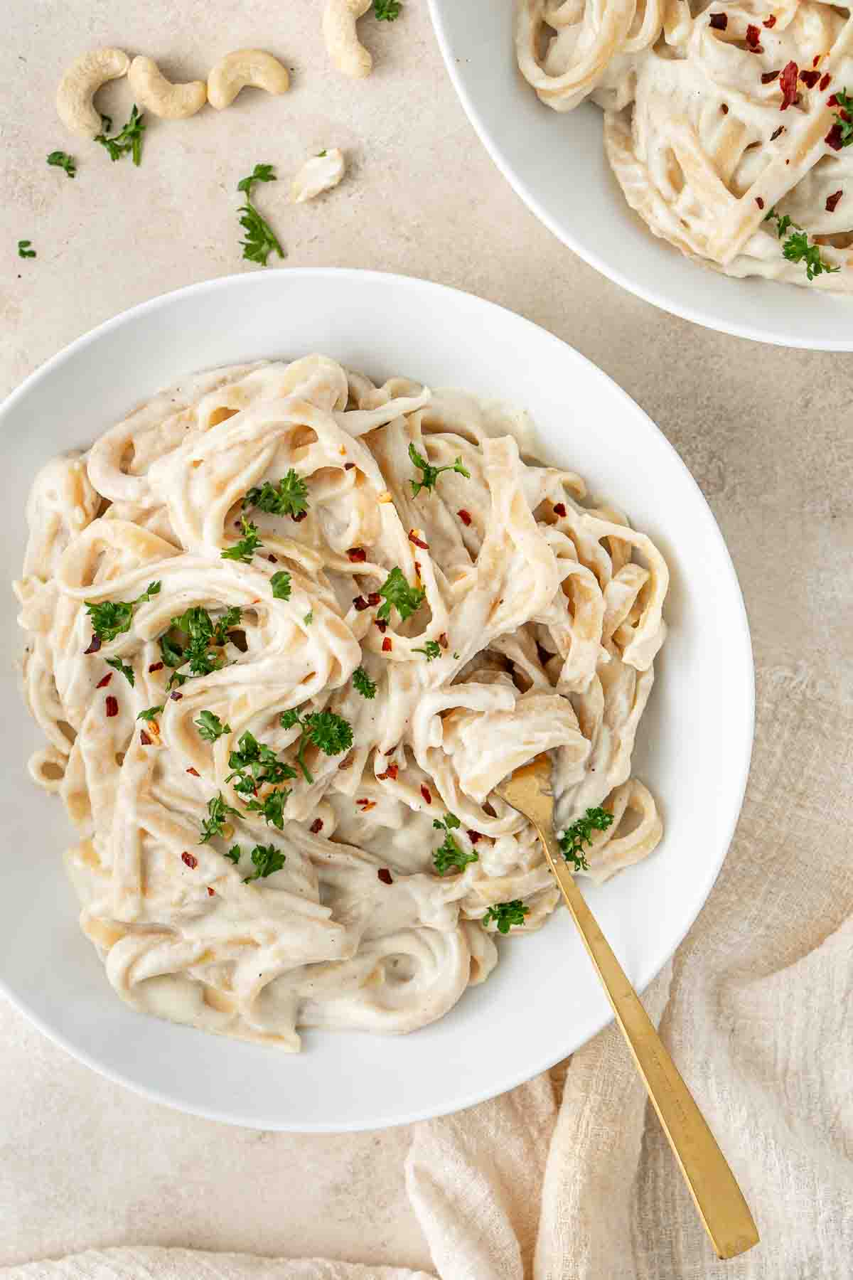 A bowl of vegan cauliflower alfredo with chilli flakes and chopped parsley. 