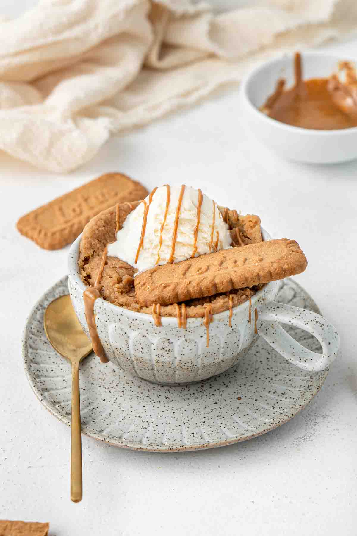 Biscoff mug cake with ice cream and a biscoff cookie.