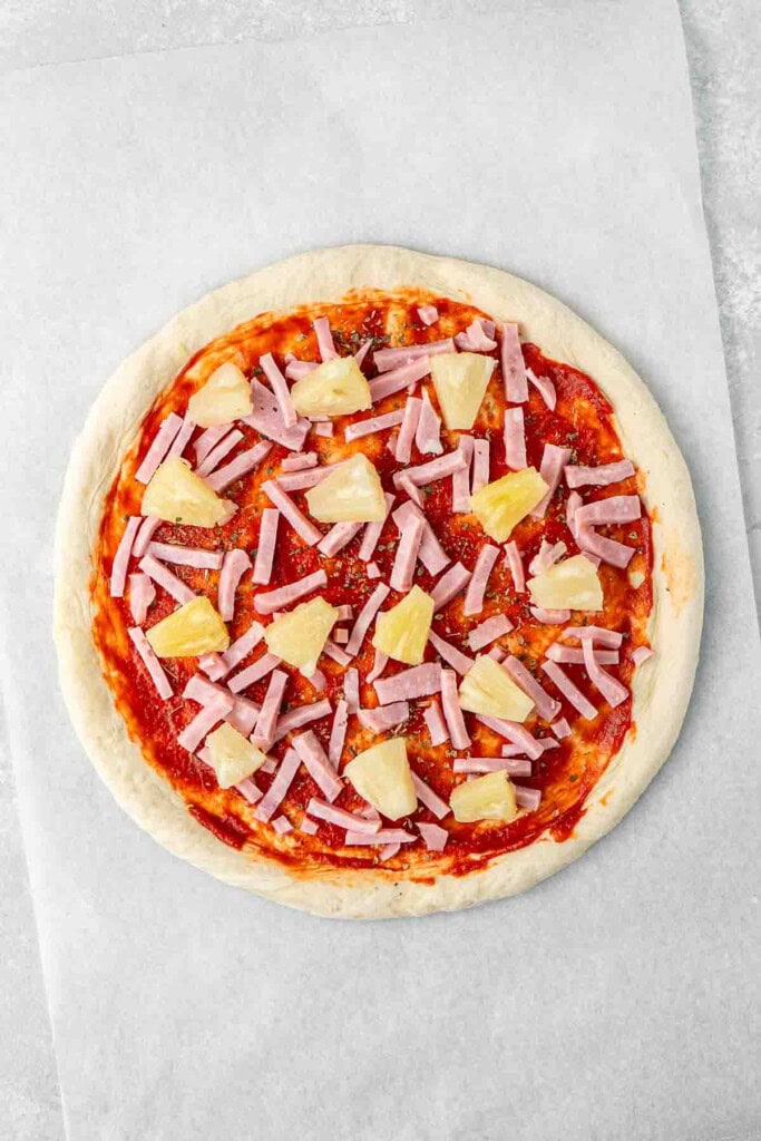 Ham and pineapple pieces laid out on the pizza base.