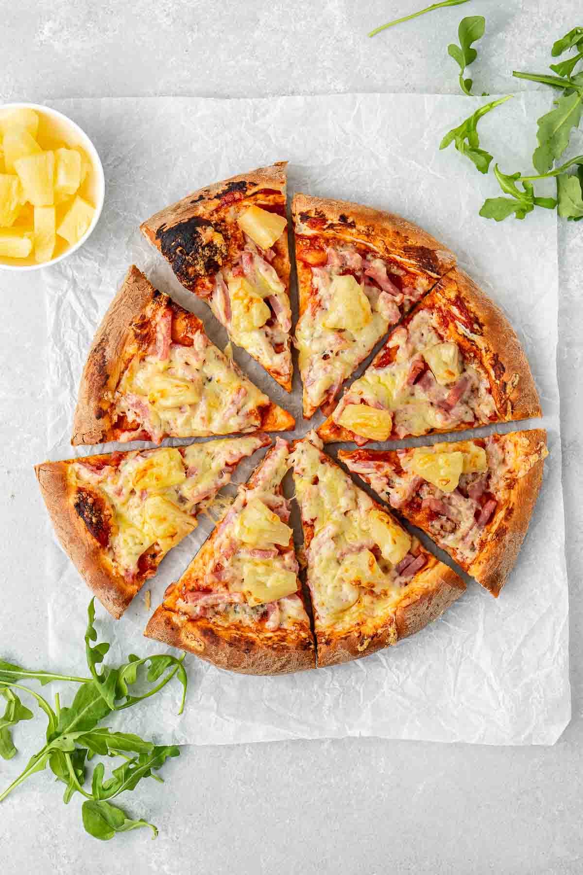 A ham and pineapple pizza cut into slices.