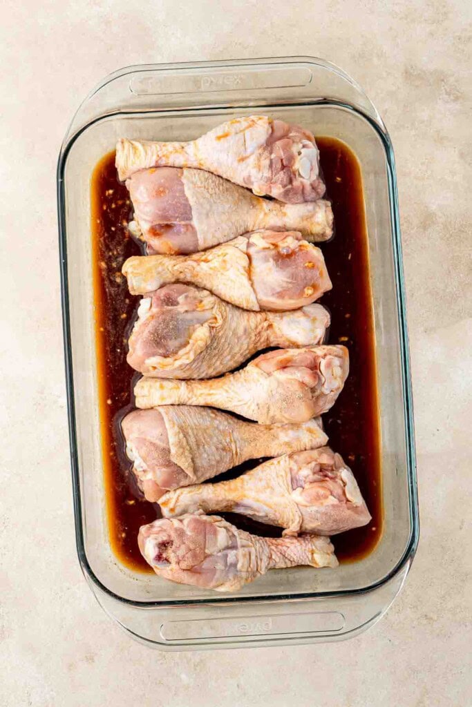 The chicken legs in a baking dish with the marinade.