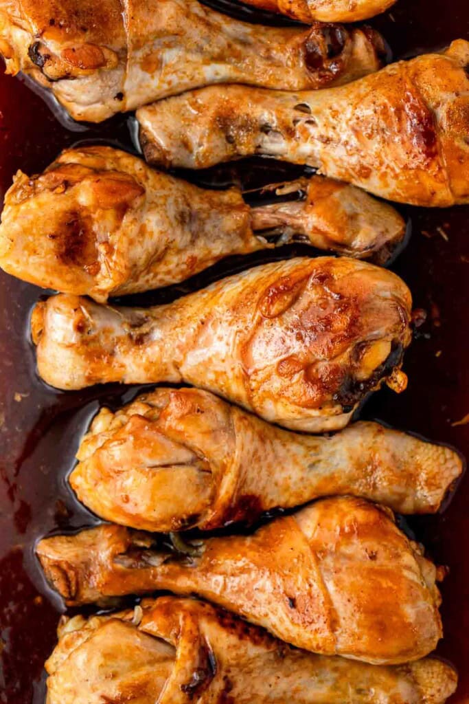 Close up of browned chicken drumsticks in the dish.