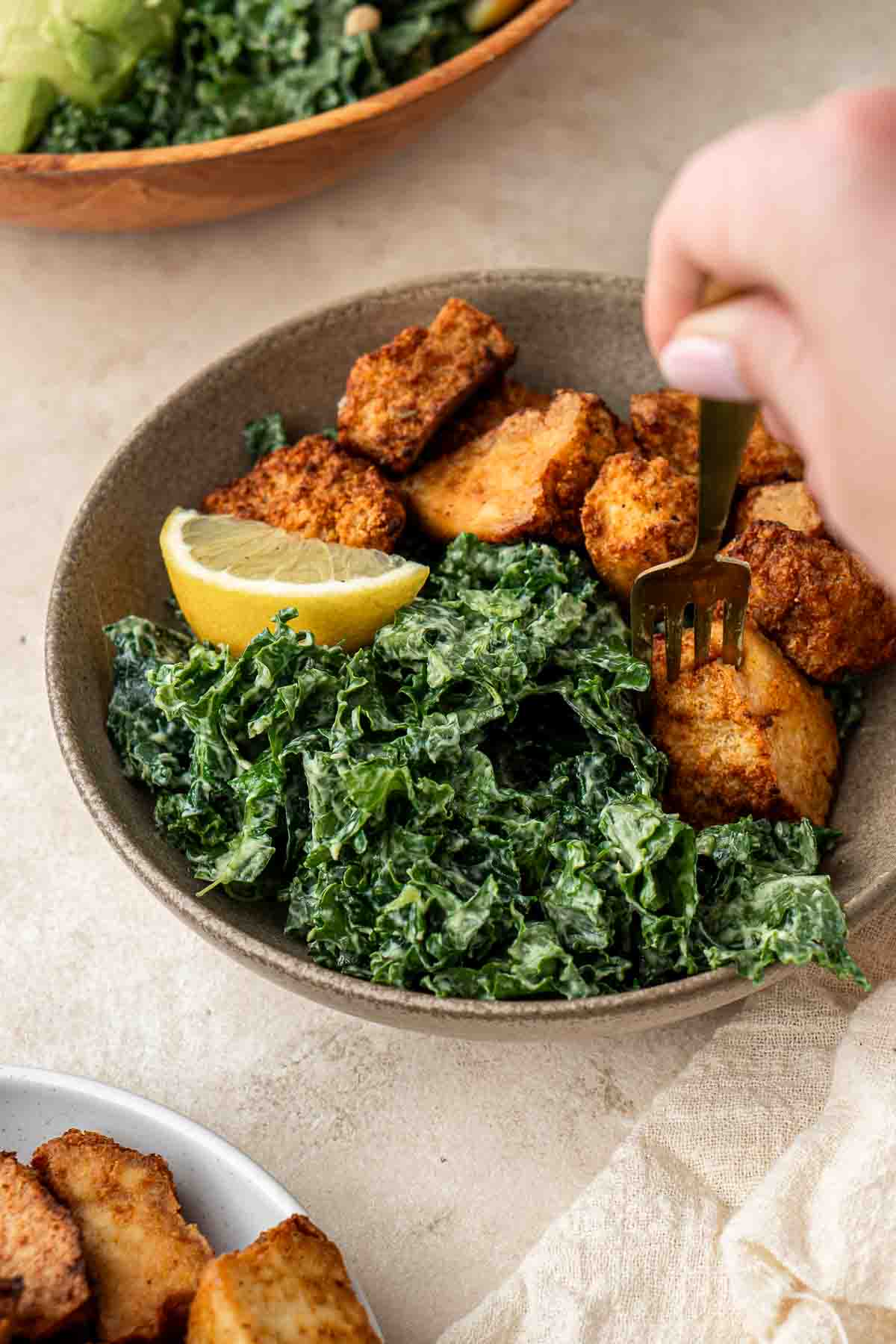 A fork taking a bite of tofu with kale salad.