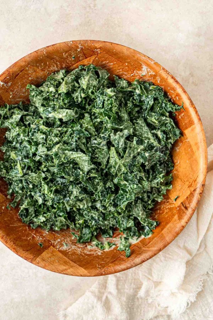 The kale tossed with the dressing in a bowl.