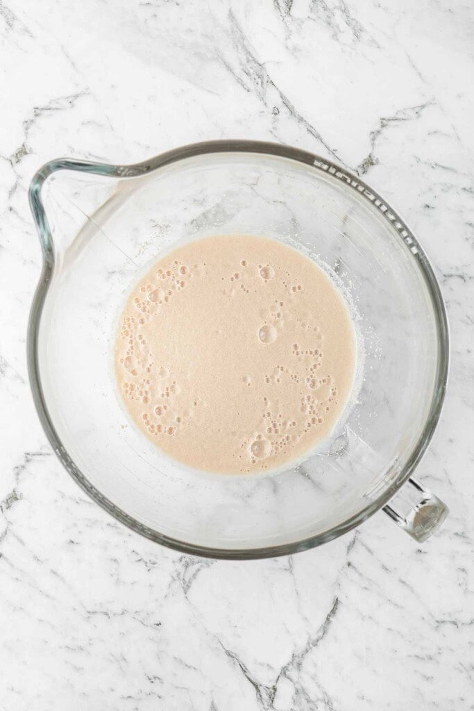 The yeast foaming in the base of a glass mixing bowl.