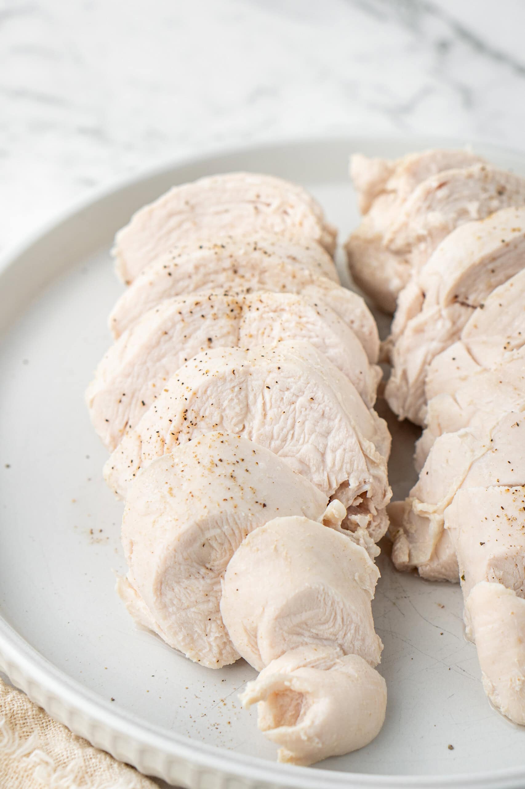 Sliced, poached chicken on a plate ready to use.