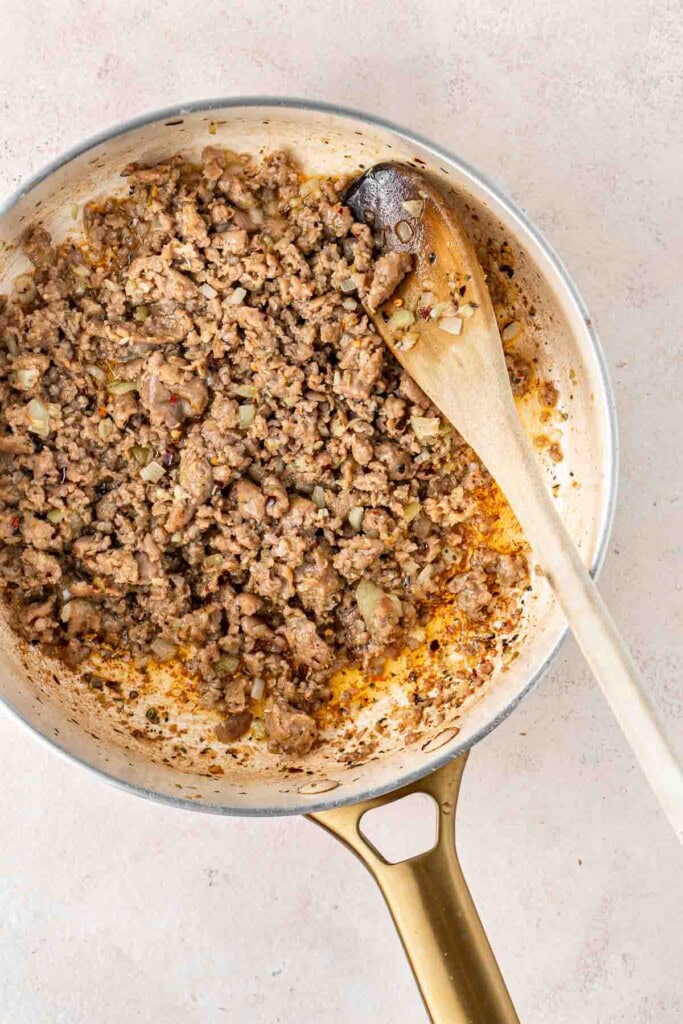 Sausage meat and onions frying in a pan.