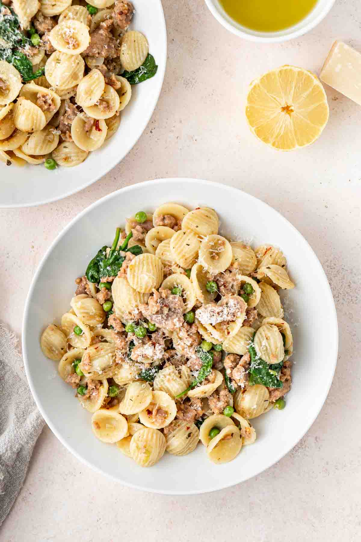 Sausage and spinach orecchiette served in white bowls.