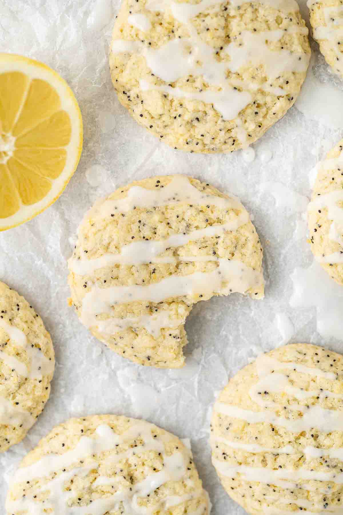 Vegan lemon poppy seed cookies, one with a bite taken.