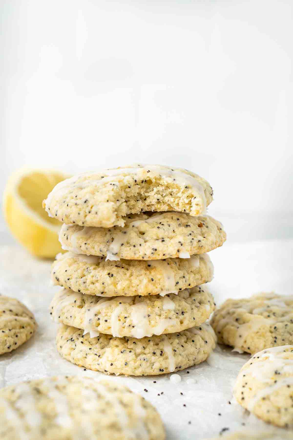 A stack of lemon poppy seed cookies, one with a bite taken.