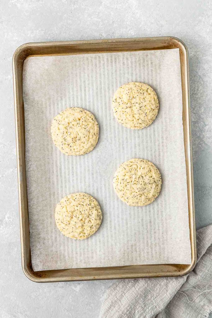 Freshly baked vegan lemon poppy seed cookies on a baking tray.