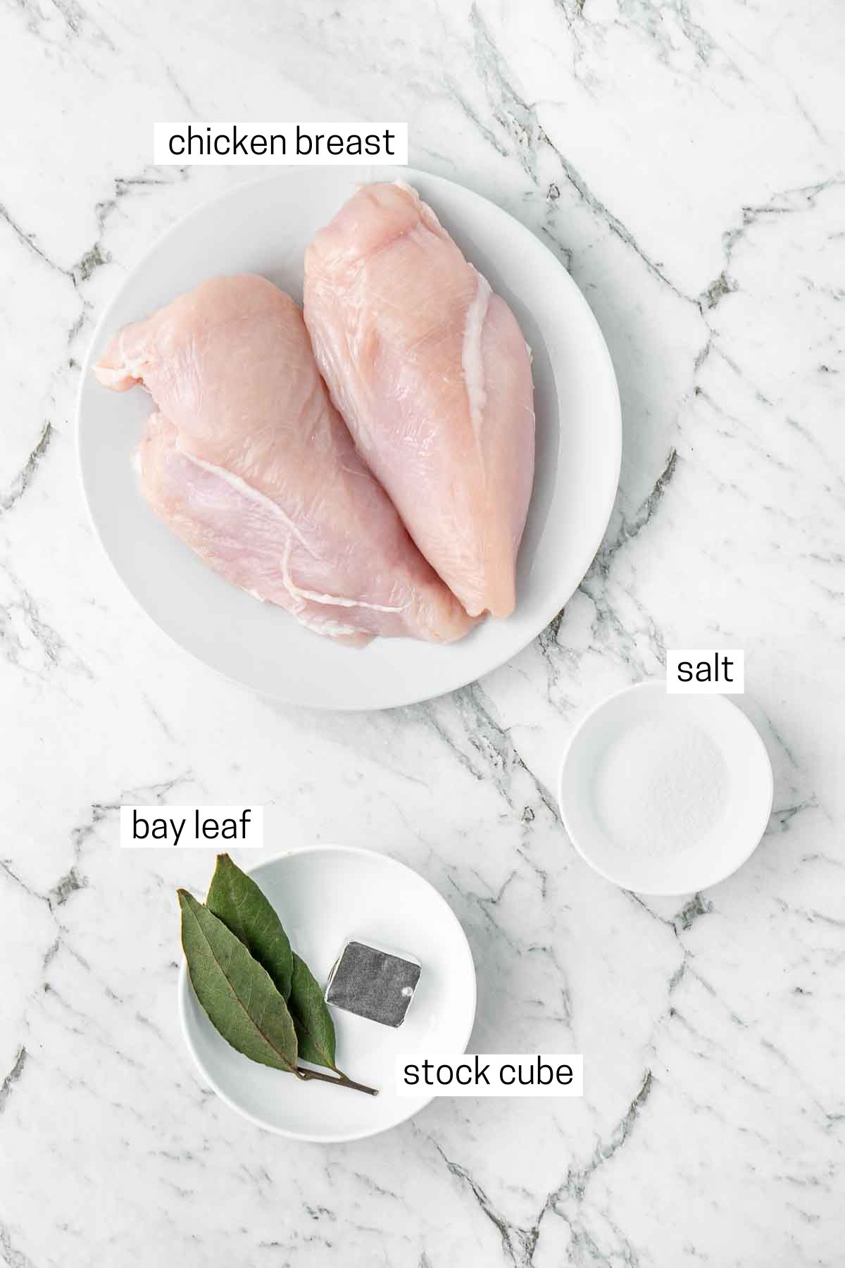 All ingredients needed to make poached chicken laid out in bowls/plates.