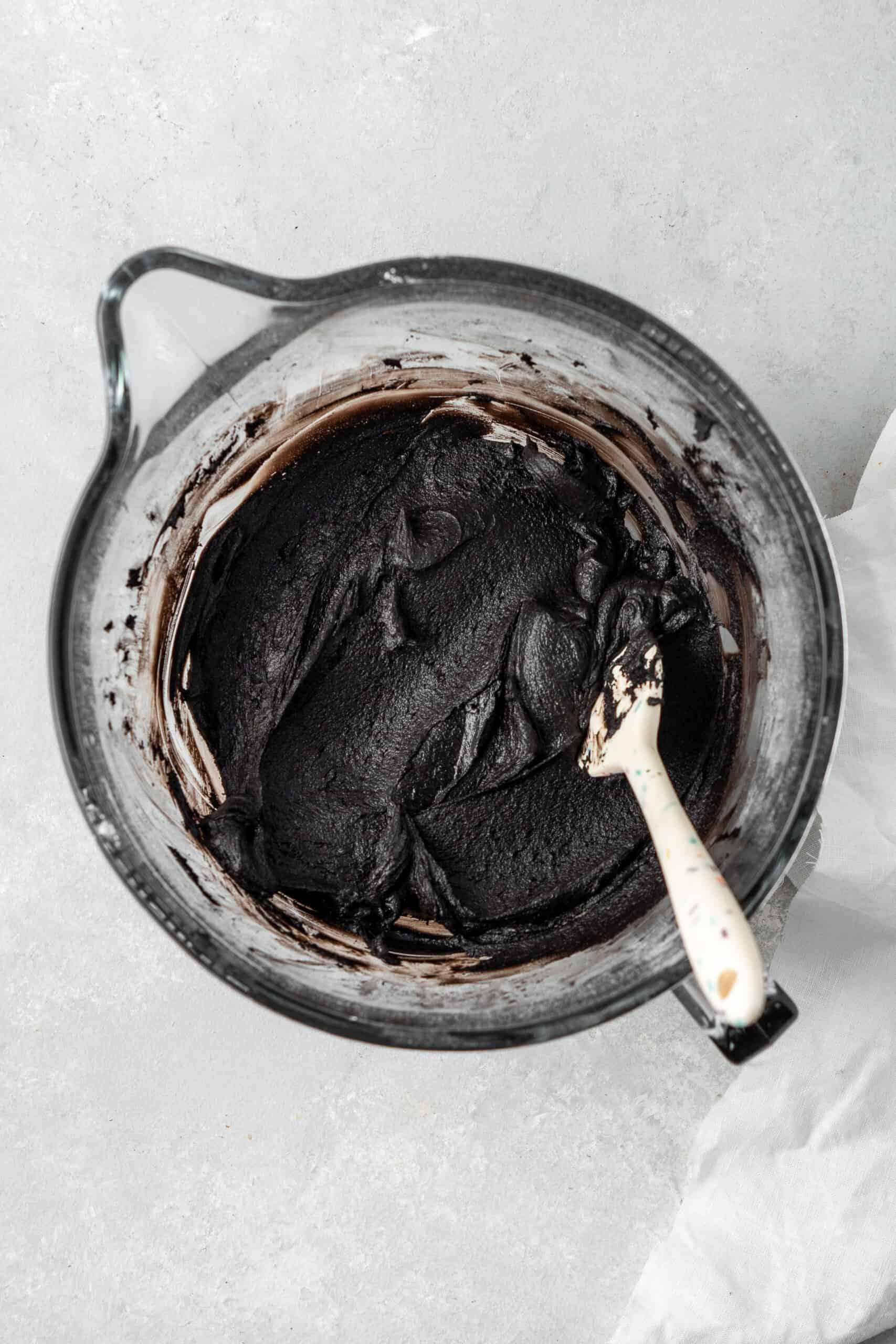 Black cocoa buttercream in a bowl with a spatula. 