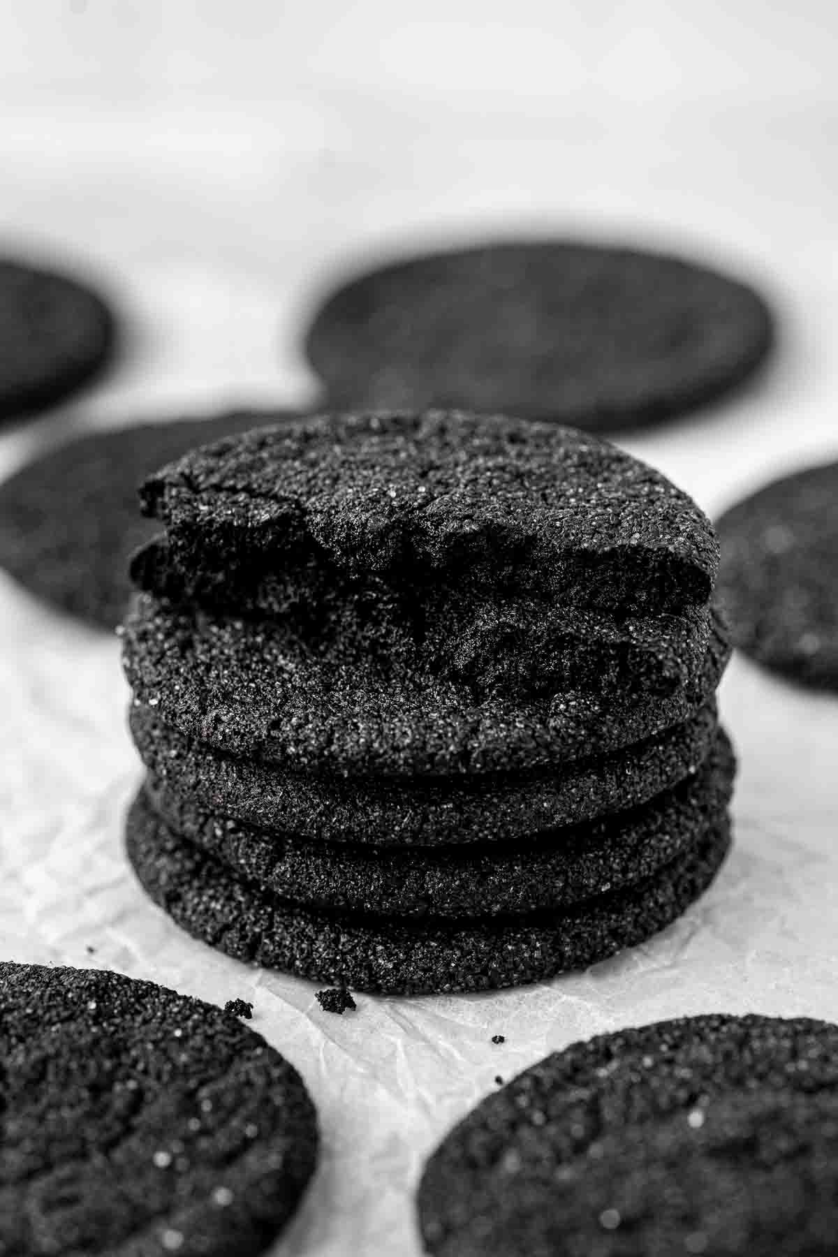 Stack of black cocoa sugar cookies, the top one broken in half.