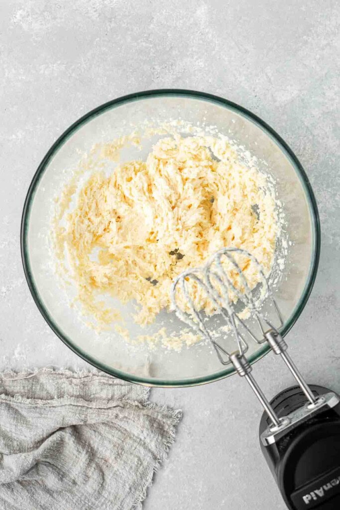 Creaming together the butter and sugar in a glass bowl with an electric mixer.