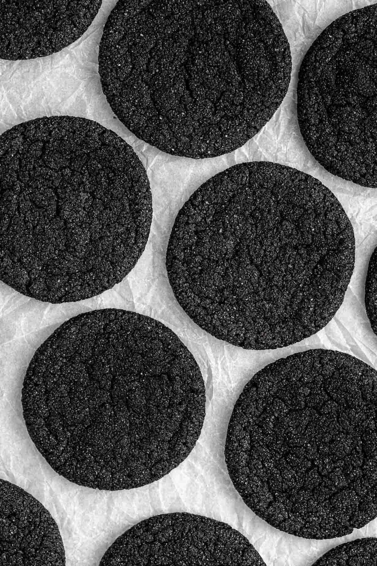 Black cocoa sugar cookies laid out on baking paper.