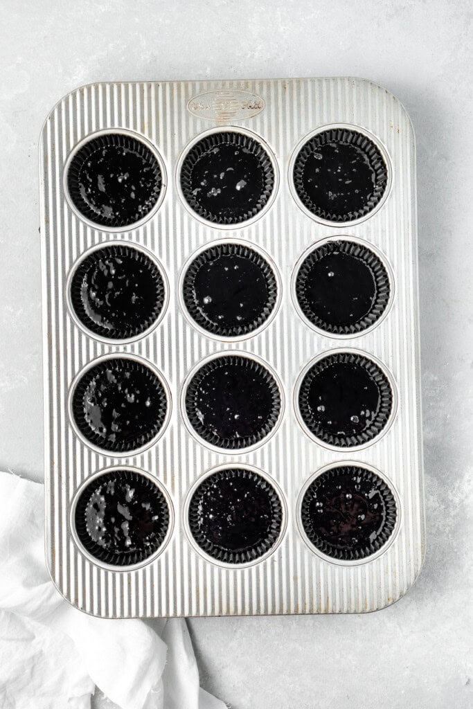 Black velvet cupcake batter in a muffin tin.