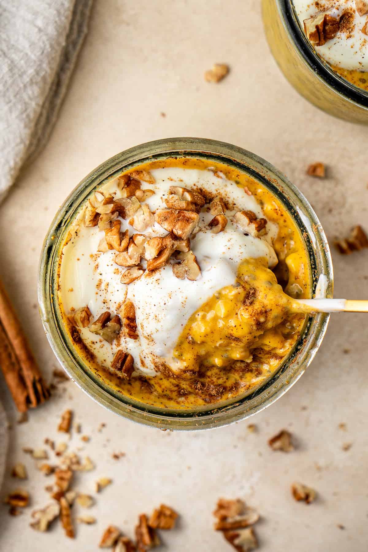 A spoon scooping out pumpkin overnight oats from a jar. 