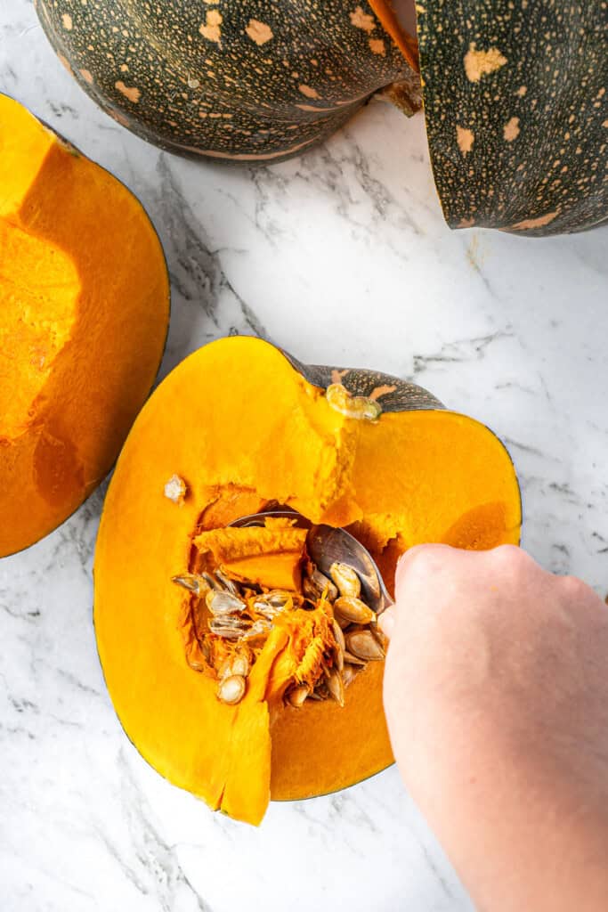 Scooping out the seeds from the pumpkin using a spoon.