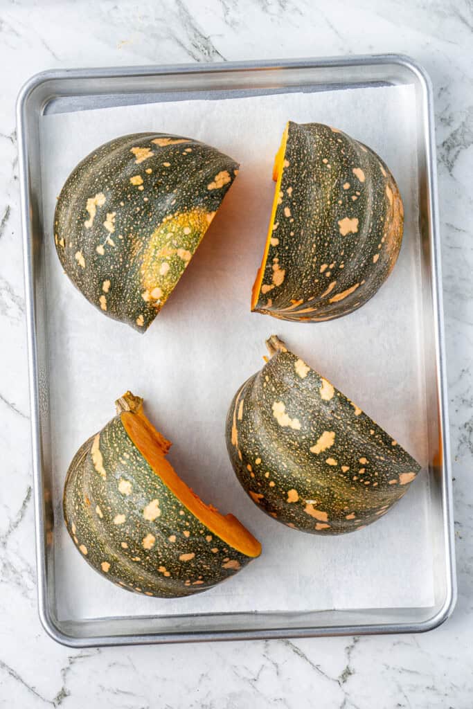 Pumpkin quarters on a baking tray.