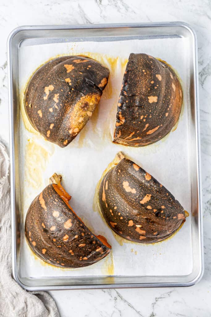 Roasted pumpkin quarters on a baking tray.