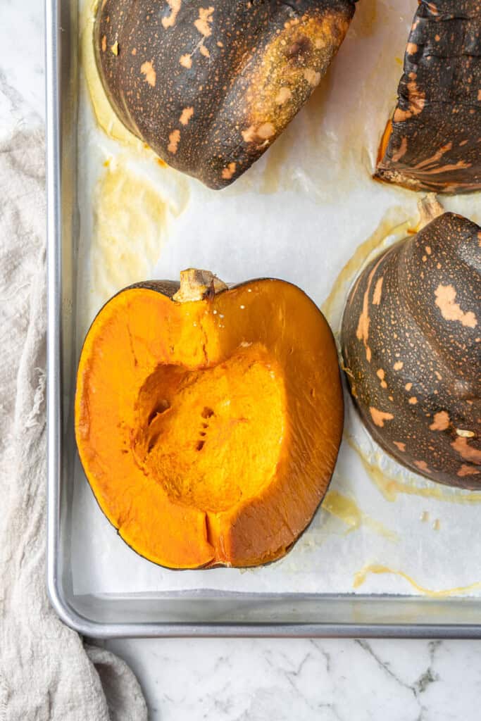 Cooked pumpkin on a baking sheet with a fork prick hole.