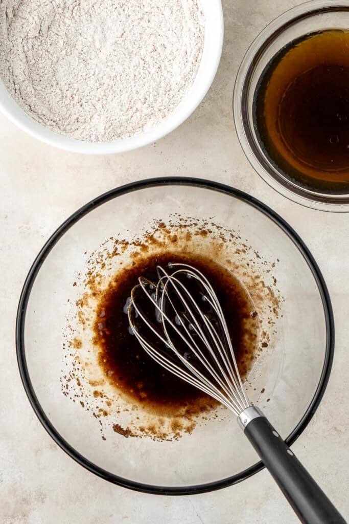 Whisking the sugar and oil in a glass mixing bowl.