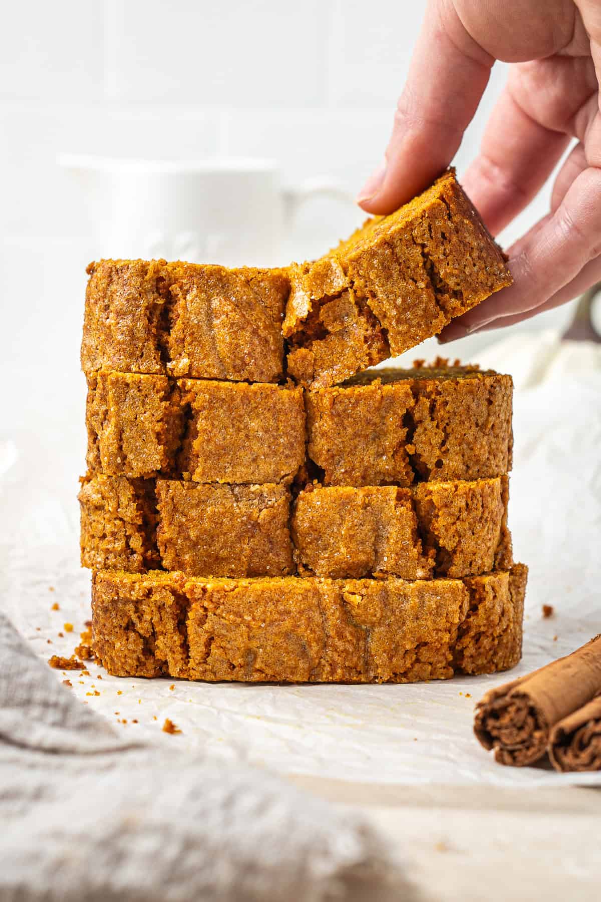 4 slices of vegan pumpkin bread with a hand taking a slice.