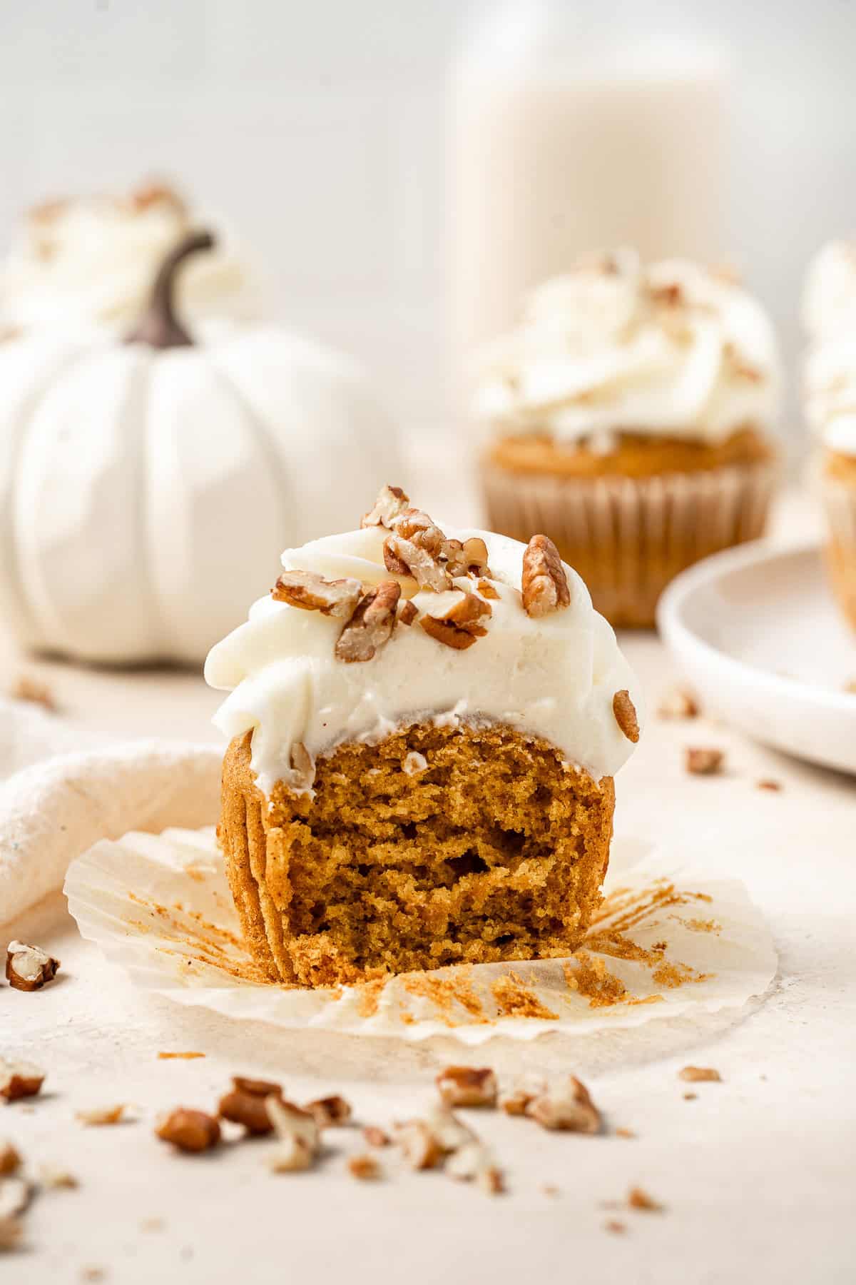 Vegan pumpkin cupcake with cream cheese frosting cut in half.