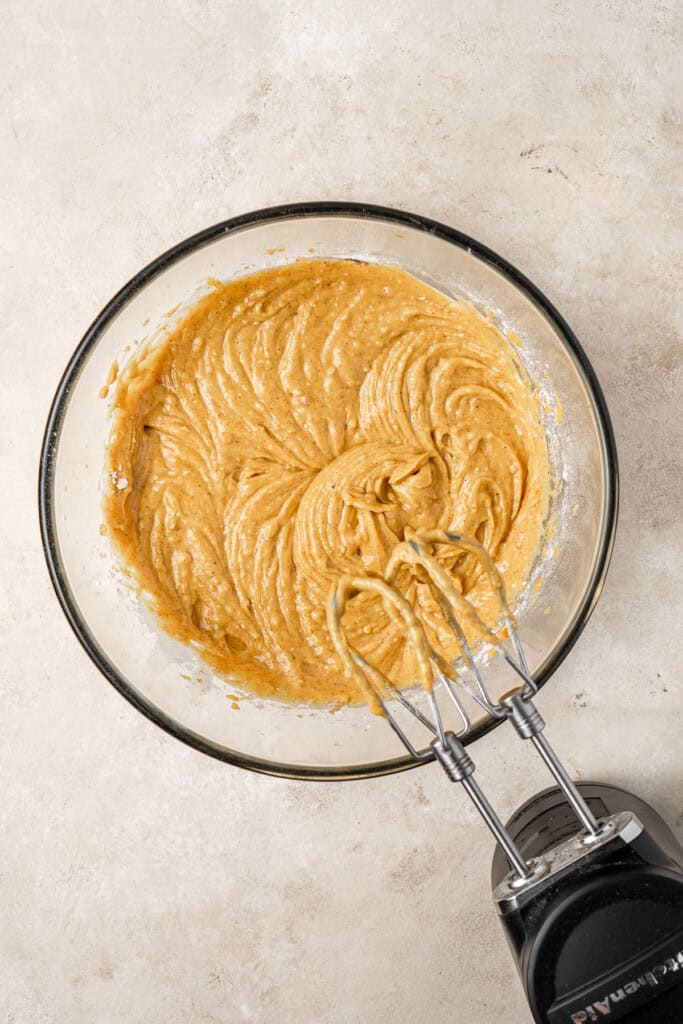 Vegan pumpkin cupcake batter in a bowl with a mixer.