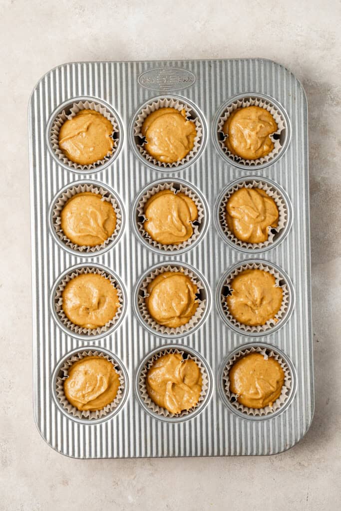 Pumpkin cupcake batter in a muffin tin.