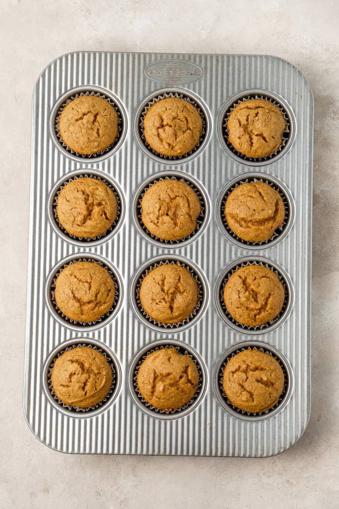 Cooked vegan pumpkin cupcakes in a muffin tin.