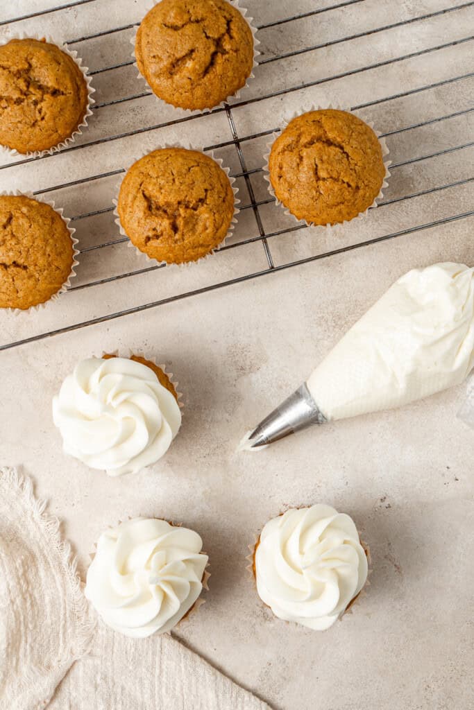 Vegan cream cheese frosting being piped onto cupcakes.