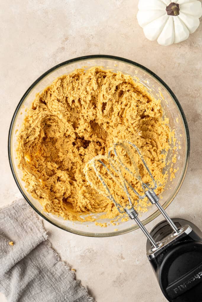 The cookie dough in a bowl with electric mixers.