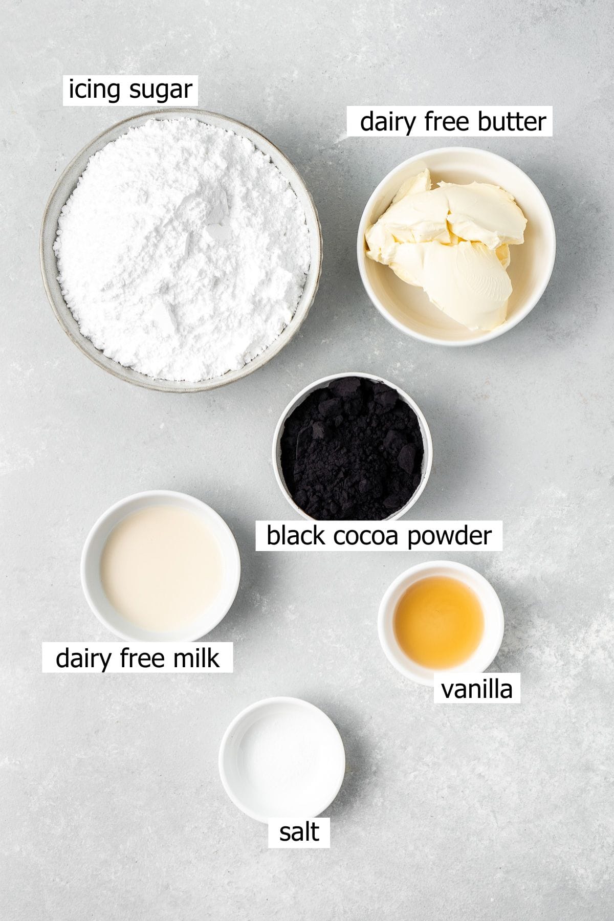 All ingredients needed to make vegan black cocoa buttercream laid out in bowls.