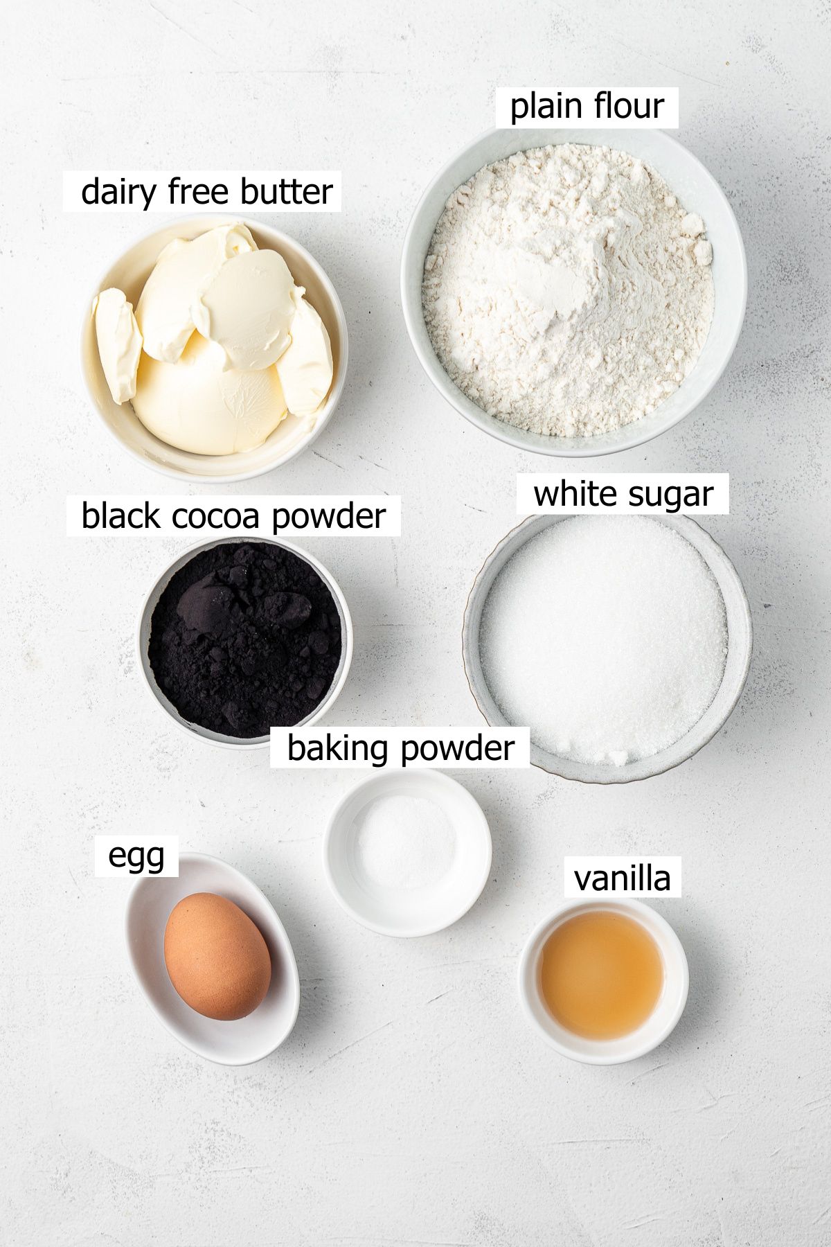 All ingredients needed to make black cocoa cookies laid out in bowls.