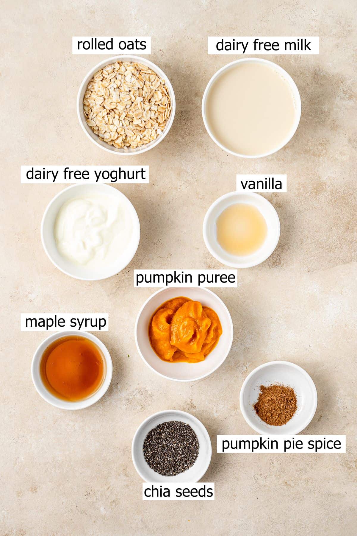 All ingredients needed to make pumpkin overnight oats laid out in small bowls.