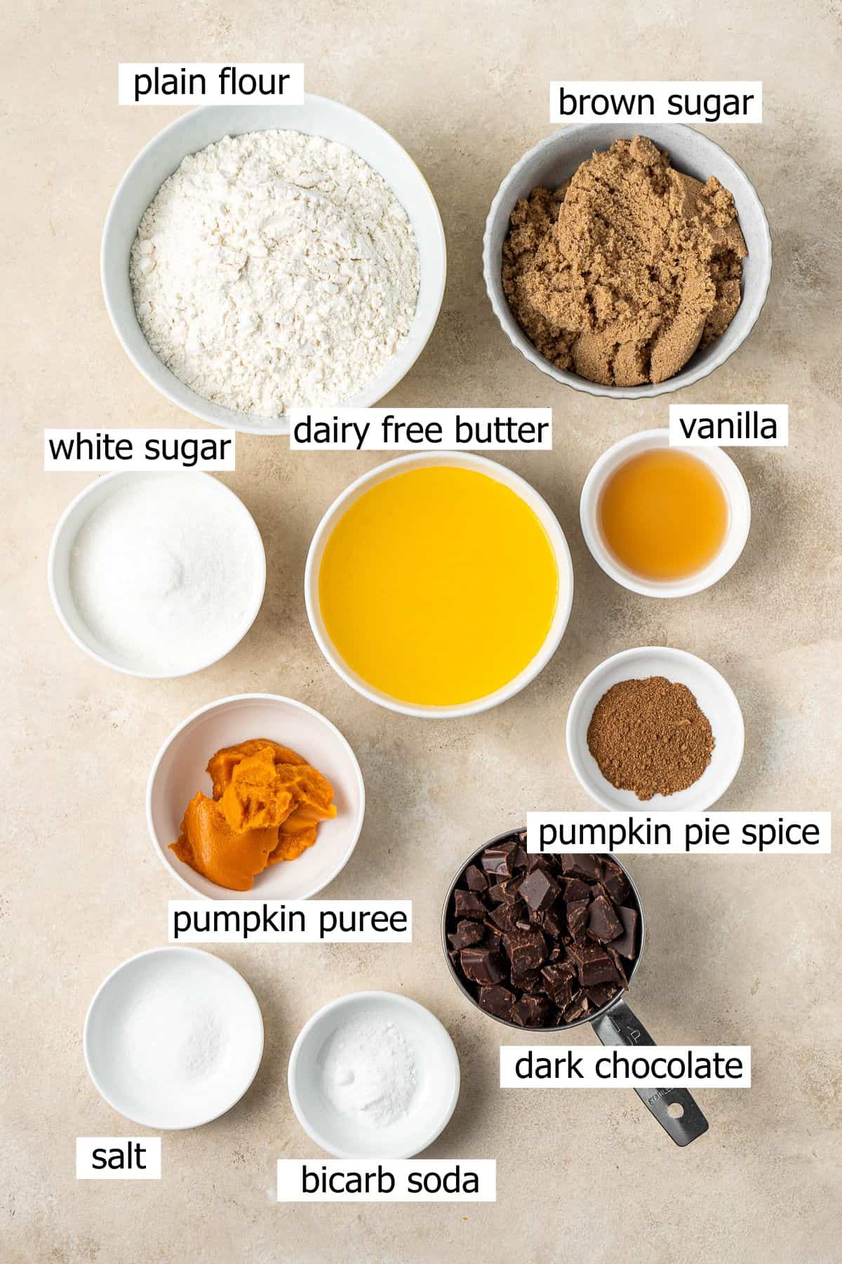 All ingredients needed to make vegan pumpkin chocolate chip cookies laid out in bowls.