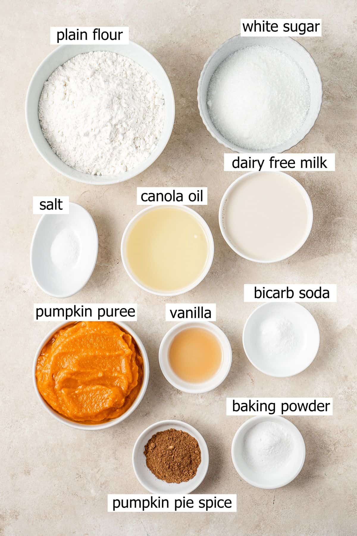 All ingredients needed for vegan pumpkin cupcakes laid out in bowls.