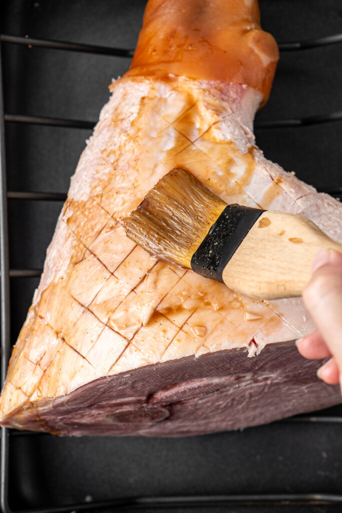 Brushing the glaze over the ham.